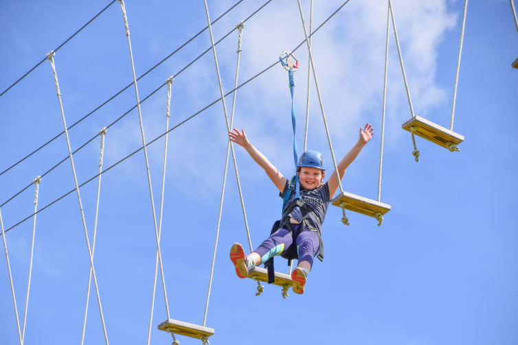 A camper in harness and helmet on our challenge course